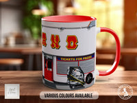 A red and white mug with the word "ANO" printed on it, along with an illustration of a ticket booth and a person.