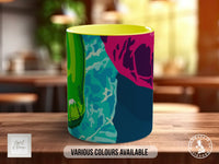 A colorful mug with a vibrant abstract design, featuring various shades of green, blue, pink, and purple.