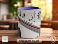 A mug with a design featuring silhouettes of people and a red stripe, placed on a wooden surface.