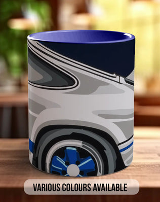 A mug with a graphic design featuring a car and a blue rim, placed on a wooden surface.