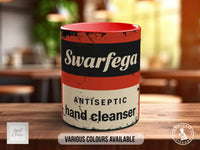 A red and white mug with the text "Swarfega Antiseptic hand cleaner" printed on it, sitting on a wooden surface.
