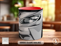 A mug with a camouflage pattern on it, sitting on a wooden surface.