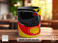 A mug with a design featuring a black Porsche car and a yellow Shell logo, sitting on a wooden surface.