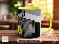 A yellow and black mug with a graphic design featuring a car or vehicle, along with the text "Various Colours Available".