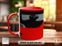 A red and black mug with a graphic design on it, sitting on a wooden surface.