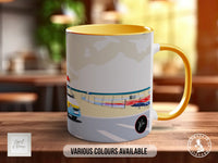 A white and yellow mug with an illustration of a car on a road, placed on a wooden surface.